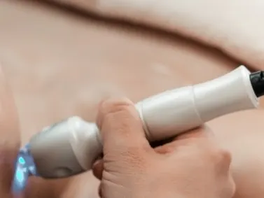 A model lying back with eyes closed during a facial treatment with a handheld device