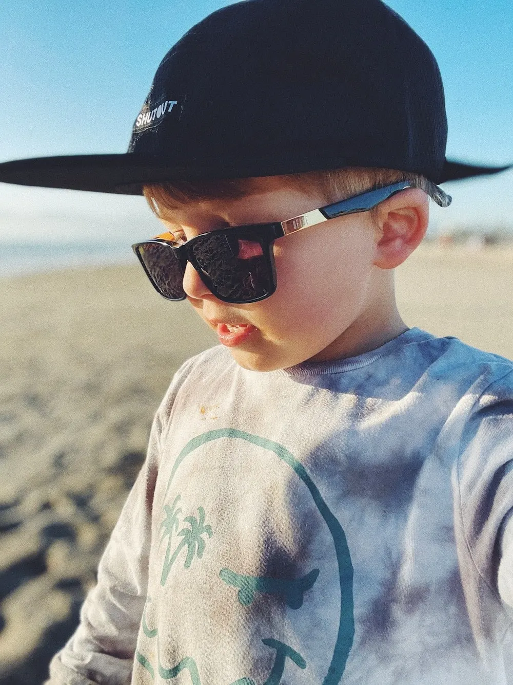 A young boy in a black cap and sunglasses on a beach