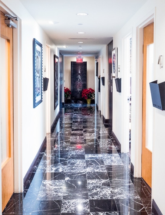 The hallway of the Greater Miami Skin & Laser Center office, with a polished marble floor and treatment-room doors on each side