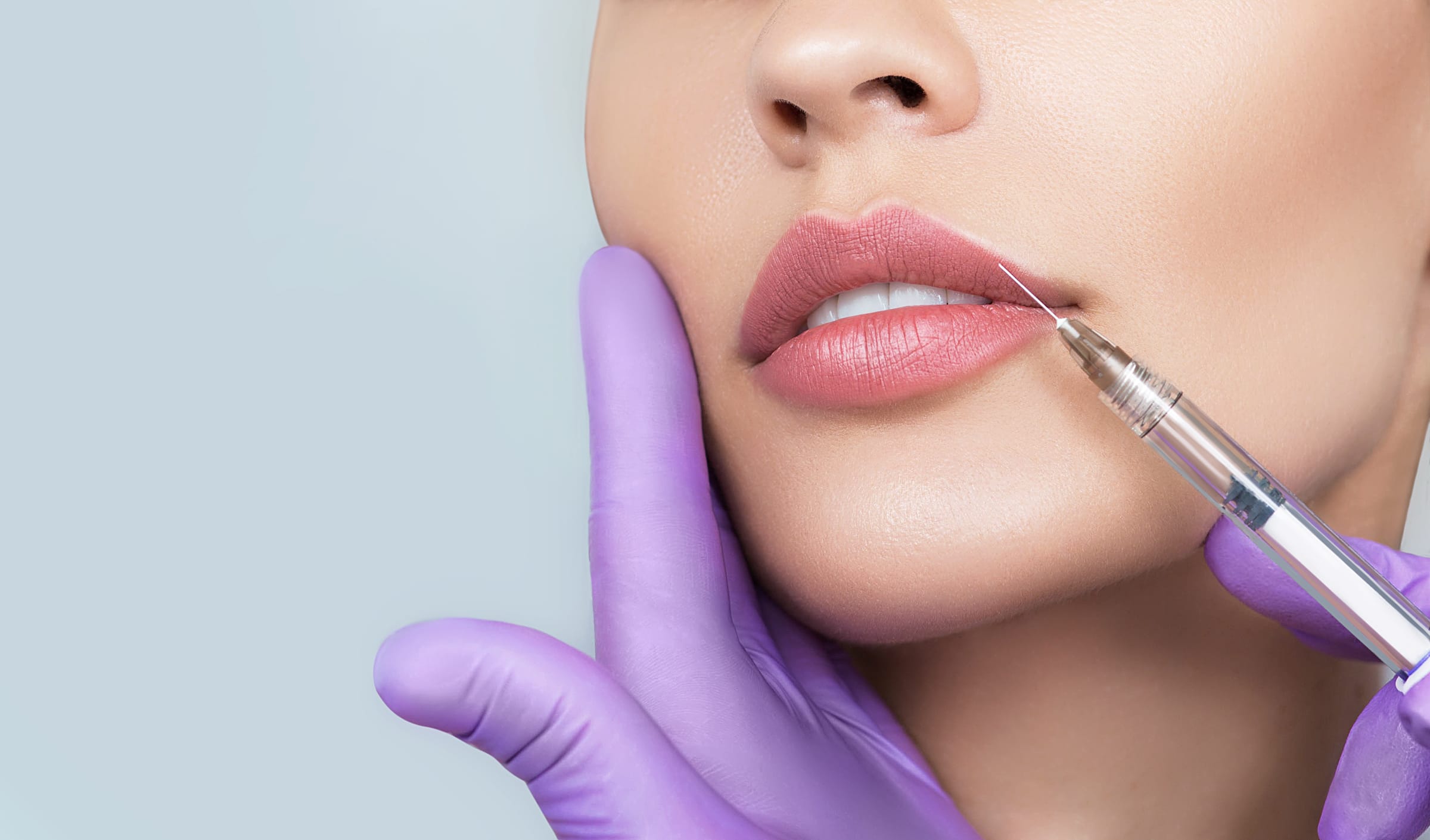 Stock photograph of a model: a purple-gloved hand steadies a woman's chin as a fine needle touches her upper lip