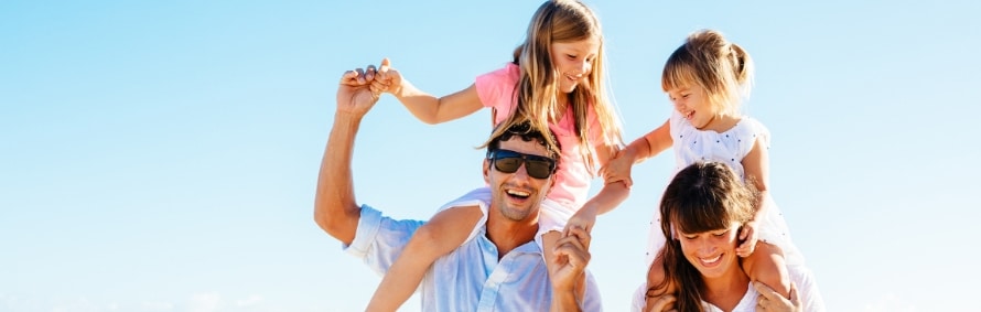 Stock photograph of models: a smiling family of four playing together on a sunny beach