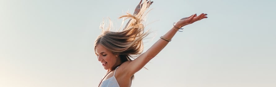A model in the open air with her arm raised and hair blowing