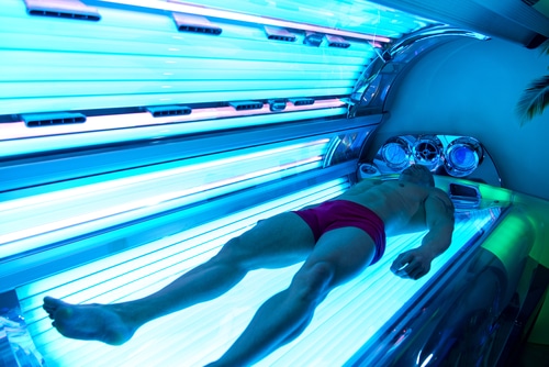 A man lying on a tanning bed under blue lights
