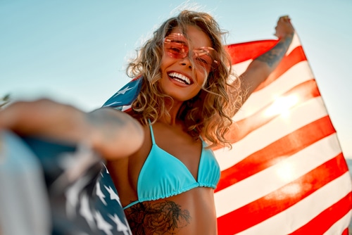Girl at Miami beach holding an American flag on 4th of July